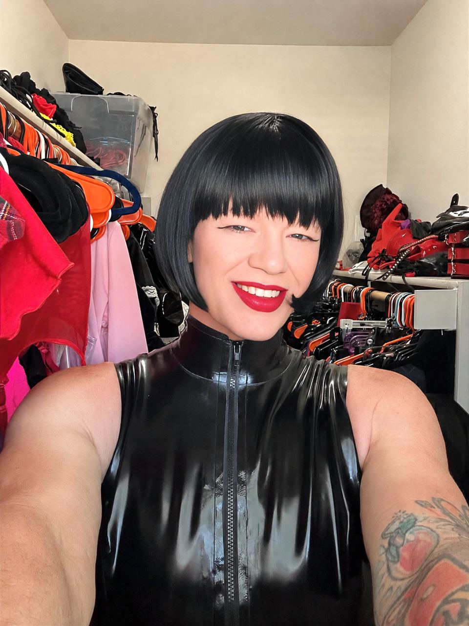TS Mistress Mia posing in black latex inside a closet