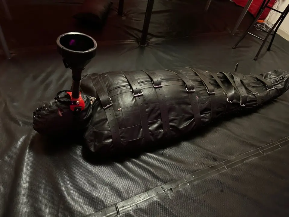 one of Ts Mistress Mia's slaves in a leather bondage bag and a funnel