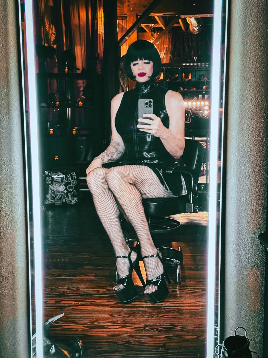 TS Mistress Mia in front of a dungeon mirror